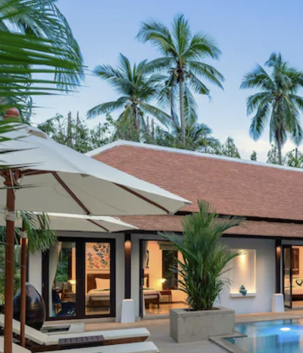 Garden villa courtyard with sun loungers, umbrellas and the pool at dusk