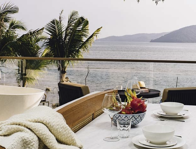 Ocean-view balcony with a freestanding soaking bathtub and breakfast set out